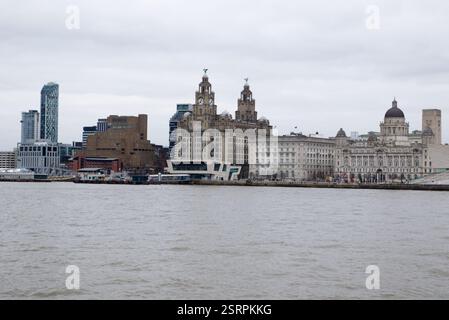 Il lungomare di Pier Head a Liverpool visto dal fiume Mersey. Gli edifici delle tre Grazie sono prominenti insieme ai moderni grattacieli Foto Stock