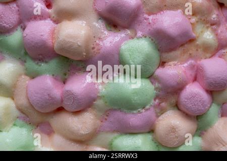 Un delizioso mix di marshmallow pastello che si fondono in una ciotola di vetro, creando una morbida esplosione di colori e una consistenza soffice. Foto Stock