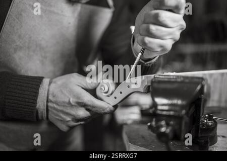Artigiano molto concentrato sulla forma di un rotolo di violino con uno scalpello Foto Stock