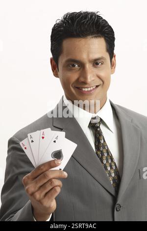Imprenditore azienda quattro assi di carte da gioco nel suo indice con il pollice e il dito medio della mano destra signor#703T Foto Stock