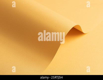 Sfondo in carta giallo dorato con una trama uniforme e curve sottili. Sfumature morbide e ombre raffinate creano un ambiente elegante, sofisticato e harmo Foto Stock