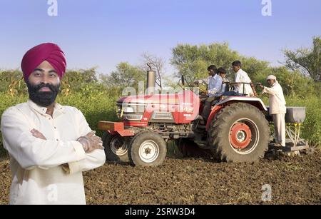 La religione Sikh l uomo con gli agricoltori utilizzando il trattore in campo il signor#779A Foto Stock