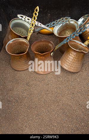 Caffettiere in rame con maniglie ornate appoggiate sulla sabbia Foto Stock