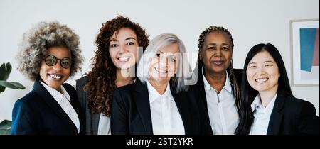 Diverse donne d'affari che sorridono alla macchina fotografica all'interno dell'ufficio della banca. Leader femminili e concetto aziendale Foto Stock