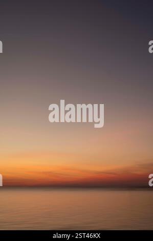 Il tramonto sulle calme acque oceaniche è caratterizzato da un cielo immenso Foto Stock
