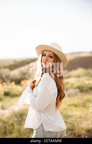Una giovane donna brillante con una camicia e un cappello bianchi Foto Stock