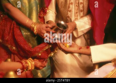Genitore con sposa e sposo che esegue vidhi rituali durante la cerimonia di matrimonio Foto Stock