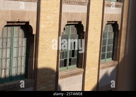 Finestre ad arco in un muro di mattoni, luci e ombre giocano sulla facciata. Dettagli architettonici, texture e tempo. Foto Stock