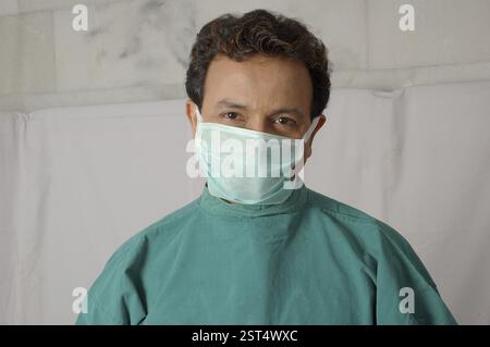 Giovane indiano medico chirurgo che indossa la maschera, verde operazione abito teatro, in clinica ospedale Foto Stock