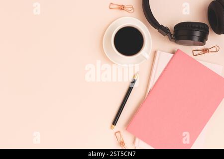 Copybook, tazza di caffè e cuffie wireless su sfondo beige. Posiziona per testo. Foto Stock
