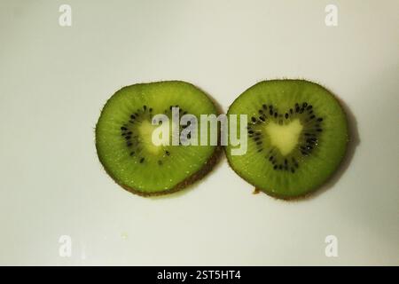 Kiwi in un taglio a forma di cuore su sfondo bianco, vista dall'alto. Cuore di frutta. Foto Stock