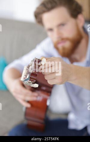 giovane adulto artigiano che sintonizza la vecchia chitarra classica Foto Stock