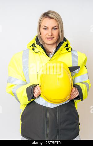 una ragazza che indossa una speciale giacca protettiva gialla e tiene in mano un casco protettivo giallo. Foto di alta qualità Foto Stock