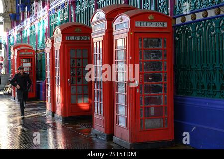 Londra, Regno Unito. 30 gennaio 2025. Un uomo cammina davanti a una fila di cabine telefoniche vecchio stile a Smithfield Market, il più grande mercato all'ingrosso della carne del Foto Stock