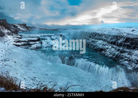 Cascata Gullfoss in Islanda. Una potente cascata glaciale che mostra toni blu ghiacciati contro le scogliere innevate su ciascun lato. Foto Stock