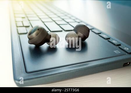 Cuffie wireless nere su laptop sullo sfondo del tavolo Foto Stock