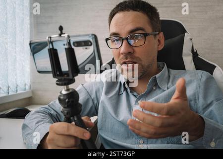 Bell'uomo che fa il video blog. Focus su smartphone. Giovane blog video spara contenuti per il suo video blog su un social network. Trasmissione in tempo reale tramite Foto Stock