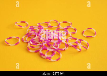 Molte fasce elastiche con combinazione rosa e bianco su sfondo giallo Foto Stock