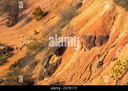 Formazione rocciosa di bauxite erosa con colori arancio brillanti in una miniera di bauxite abbandonata Foto Stock