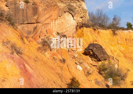 Formazione rocciosa di bauxite erosa con colori arancio brillanti in una miniera di bauxite abbandonata Foto Stock