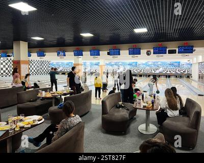 Leopoli, Ucraina - 16 febbraio 2025: Persone che si divertono a giocare a bowling con divertimento e cibo. Foto Stock