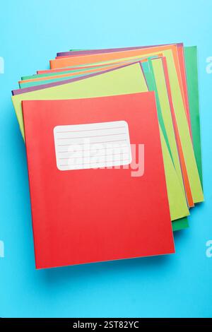 Una pila di copybook colorati su sfondo azzurro, vista dall'alto. Cancelleria scolastica Foto Stock