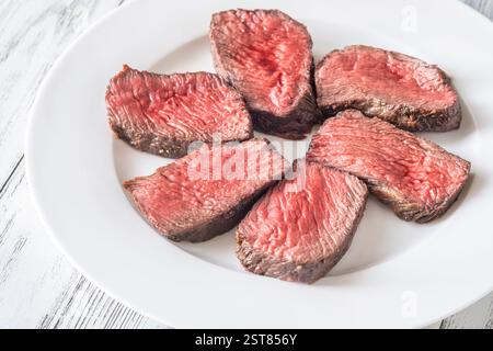 Tenera bistecca di mignon in filetto, perfettamente cotta, tagliata a fette ed elegantemente presentata su un piatto Foto Stock