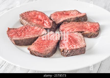 Tenera bistecca di mignon in filetto, perfettamente cotta, tagliata a fette ed elegantemente presentata su un piatto Foto Stock