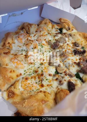 Gusta una pizza deliziosa e soddisfacente, condita generosamente con Cheddar e carne salata Foto Stock