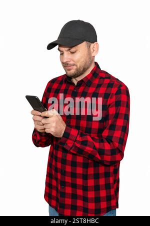 Uomo ritagliato con berretto nero e camicia a quadri rossa con SMS su cellulare nero Foto Stock