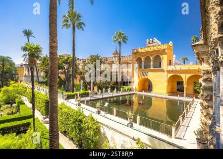 L'Alcázar di Siviglia, storico palazzo reale nella città di Siviglia, Andalusia, Spagna. Sereni giardini del palazzo con piscina riflettente e vegetazione lussureggiante. Foto Stock