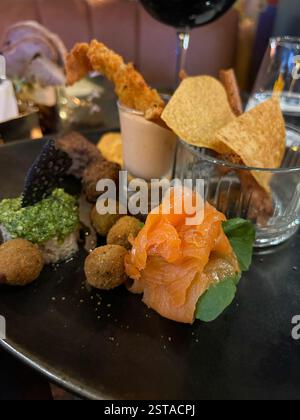 Questa selezione di antipasti splendidamente placcati presenta un elegante mix di sapori e consistenze. Il piatto presenta un delicato salmone affumicato su verdure fresche Foto Stock