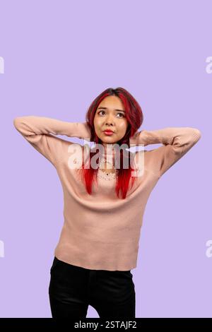 Ritratto in studio di una giovane donna con i capelli rossi che tiene la testa con le mani e guarda verso l'alto, esprimendo preoccupazione o pensiero profondo Foto Stock