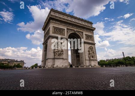 Francia, Parigi. L'Arco di Trionfo si erge orgogliosamente sotto un cielo parzialmente nuvoloso, catturato da una prospettiva a basso angolo. Questo punto di vista mette in evidenza il monu Foto Stock
