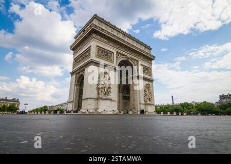 Francia, Parigi. L'Arco di Trionfo si erge orgogliosamente sotto un cielo parzialmente nuvoloso, catturato da una prospettiva a basso angolo. Questo punto di vista mette in evidenza il monu Foto Stock