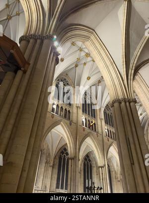 Guardando in alto il soffitto a volta della York Minster di notte, con boss d'oro che brillano mentre le vetrate colorate appaiono nere contro il cielo notturno Foto Stock