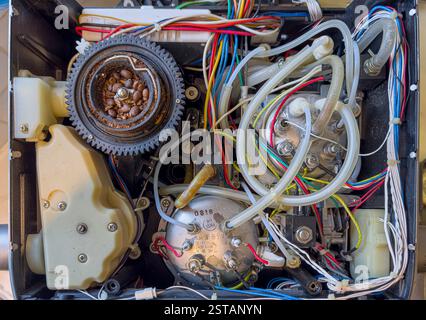Vista dall'alto verso il basso dell'interno di una macchina da caffè con macinacaffè, che rivela una complessa gamma di fili colorati, componenti e il macinacaffè esposto Foto Stock