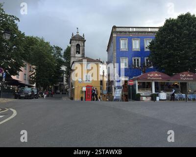 Palazzo Nazionale di Sintra. Edificio blu con finiture bianche e finestre ad arco. Edificio giallo con una torre dell'orologio. Cabina telefonica rossa britannica. Cartello Cafe Paris Foto Stock