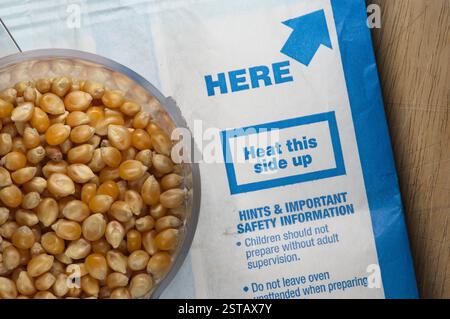 Una tazza di popcorn seduti su un sacchetto di popcorn per microonde Foto Stock
