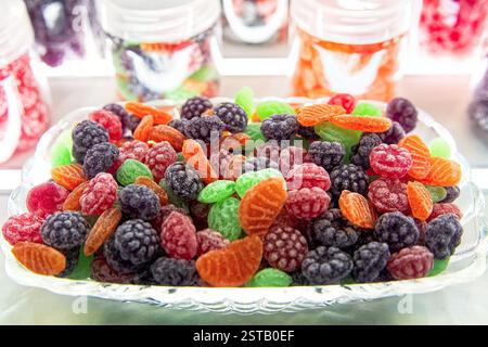 Mucchio di caramelle colorate a forma di frutti di bosco e frutta in un recipiente di vetro. Dolci naturali focalizzati sulla selezione. Foto Stock