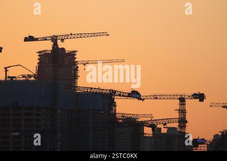 Cantiere al tramonto, gru sagomate, Shenzhen, Guangdong, Cina - febbraio 2025 concetti: Economia, rallentamento Foto Stock