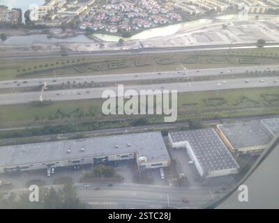 Vista aerea di un'autostrada a Miami. Lussureggianti alberi verdi formano un cartello di benvenuto sopra la strada. Le auto viaggiano sotto il frondoso tettuccio. Approccio ecocompatibile alla t Foto Stock