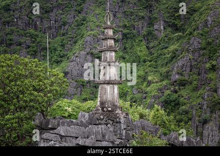 Pagoda tradizionale in pietra circondata da lussureggiante foresta verde e montagne rocciose presso l'Hang Mua a Ninh Binh Vietnam Foto Stock