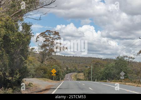 Tasman Highway, costa est Tasmania, Australia - 23 dicembre 2024: Strada autostradale a due corsie sulla costa est della Tasmania con cartello di confluenza di corsia Foto Stock