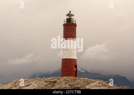 L'iconico faro a righe rosse e bianche si erge alto su un affioramento roccioso contro un cielo spettacolare. I suoi colori accesi contrastano con lo sfondo morbido Foto Stock