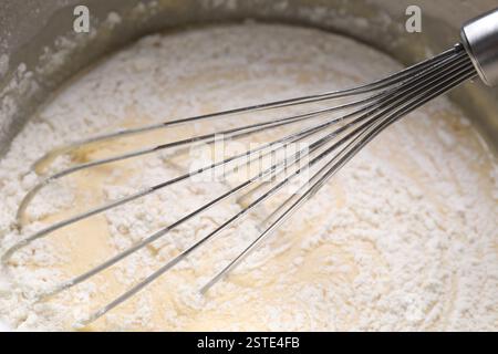 Frusta e ciotola di impasto, vista ravvicinata Foto Stock