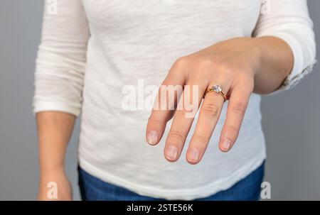 Primo piano anonimo di una mano che mostra un elegante anello di fidanzamento a diamanti, a simboleggiare l'impegno e il lusso Foto Stock
