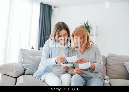 Guardando vecchie foto. Madre e figlia sono insieme a casa. Foto Stock
