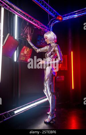 biondo come cyber robot. Ragazza in brillante armatura argento al neon Foto Stock