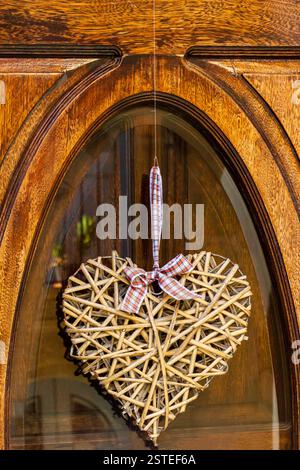 Ornamento rustico in legno a forma di cuore su una porta di legno splendidamente intagliata Foto Stock
